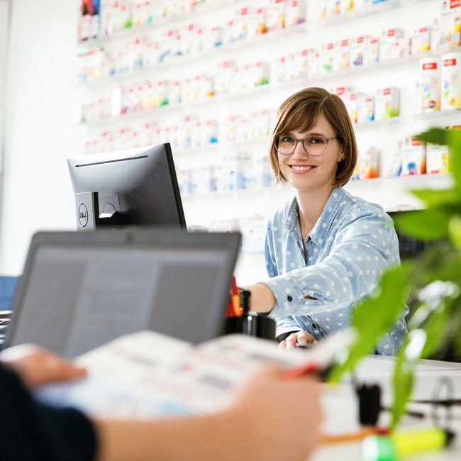 Mitarbeiterin sitzt im Büro vor einem Computer und lächelt